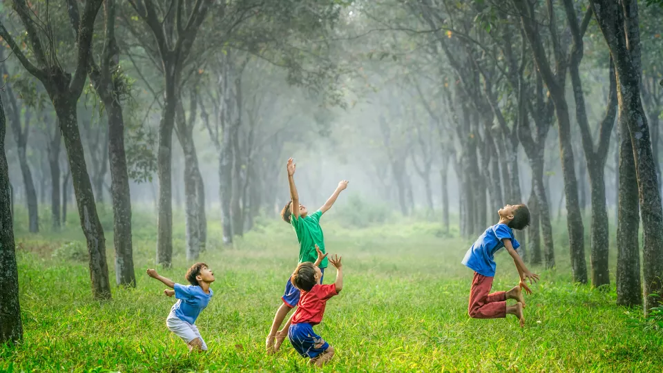 Children on a green field. Photo: Unsplash.