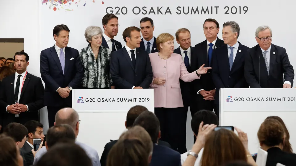 People in formal attire standing in front of a crowd at a press conference.