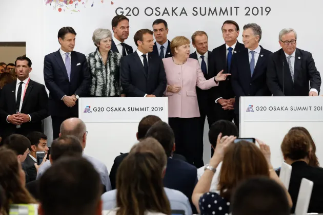 People in formal attire standing in front of a crowd at a press conference.