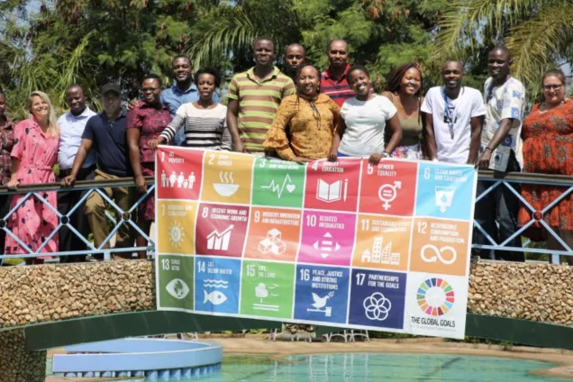 Participants in the course Land is Life standing holding up a sign with the SDG:s. Photo.