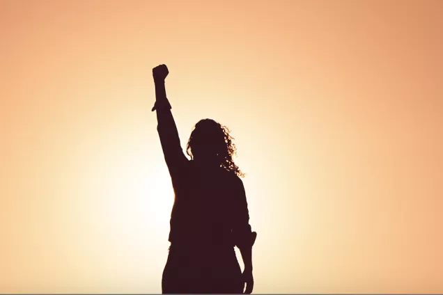 A woman with her hand raised up. Photo: Unsplash.