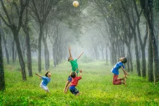 Children on a green field. Photo: Unsplash.