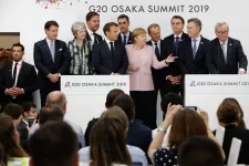 People in formal attire standing in front of a crowd at a press conference.